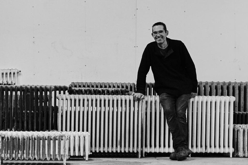 Person standing next to stock of reclaimed cast iron old radiators